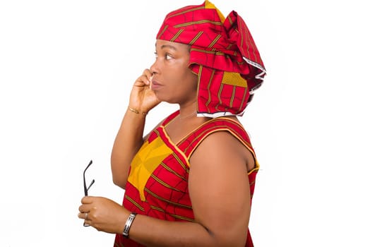mature woman in red african outfit, talking on smart phone with smile. Profile woman with glasses in her hand. Mobile communication, isolated on white background.