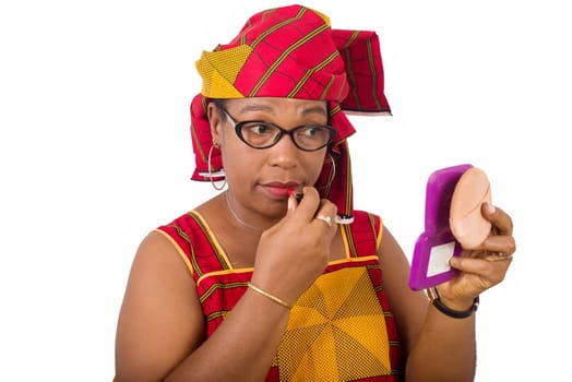 beauty, makeup and elderly people concept in red african outfit - smiling senior woman applying lipstick on her lips looking in small mirror on white background