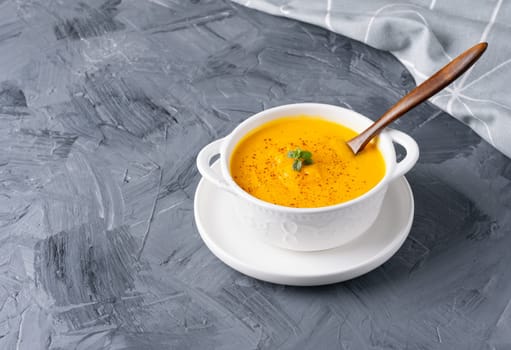 Pumpkin soup with croutons on grey background, with copy space for text.
