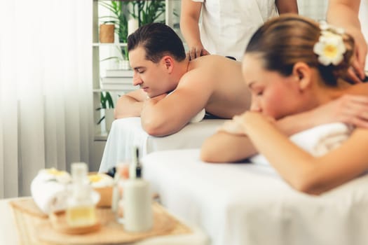 Hot stone massage at spa salon in luxury resort with day light serenity ambient, blissful couple customer enjoying spa basalt stone massage glide over body with soothing warmth. Quiescent