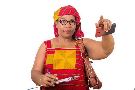 mature businesswoman standing on white background with notebook in hand beckoning to someone.