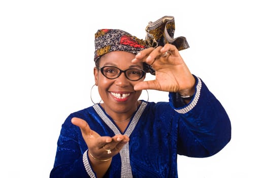 mature african woman standing in blue dress on white background going smiling on camera.