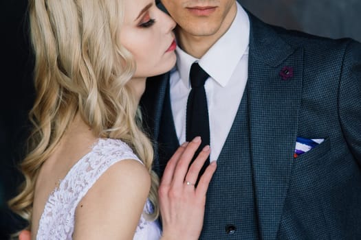 Cute wedding couple in the interior of a classic studio. They kiss and hug each other.