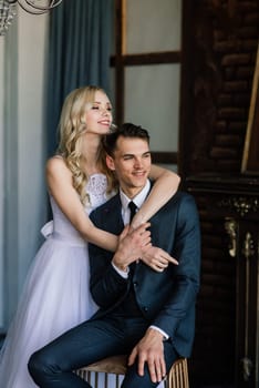 Cute wedding couple in the interior of a classic studio. They kiss and hug each other.