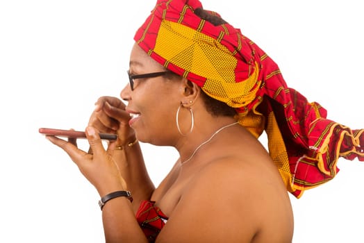 mature woman in traditional dress standing on white background communicating to mobile phone while smiling.