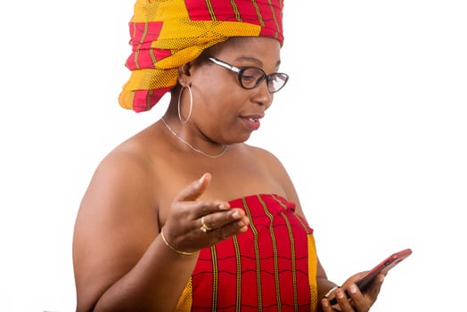 mature woman in traditional dress standing on white background looking at cell phone while smiling.