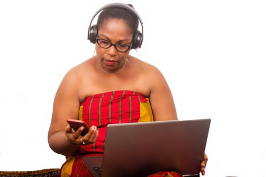 mature woman in loincloth sitting on white background with laptop watching mobile phone.