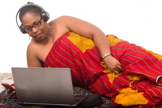 mature woman on white background listening to music and looking at laptop smiling.