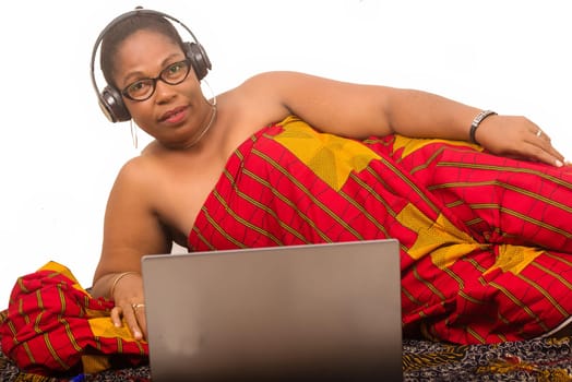 mature woman on white background listening to music while smiling using laptop.