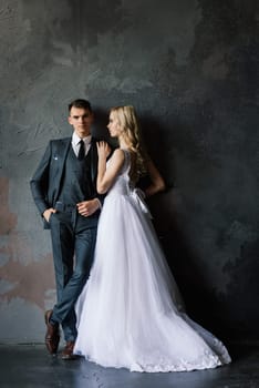 Cute wedding couple in the interior of a classic studio. They kiss and hug each other.