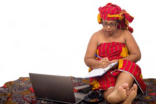 mature woman sitting on the floor writing on notepad.