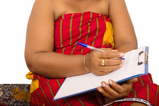 mature woman in loincloth sitting on the floor writing on a notepad.