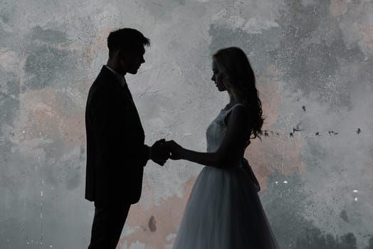 Cute wedding couple in the interior of a classic studio decorated. They kiss and hug each other.