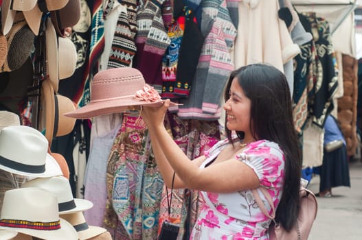 Young Woman Shopping for Traditional Hats at an Outdoor Market Stall. High quality photo
