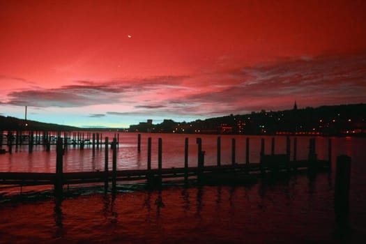 Vibrant twilight saturates a serene waterscape with crimson reflections over wooden docks in Houghton, Michigan, Fall 2017