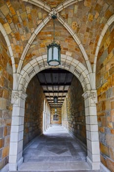 Stone corridor architecture showcasing medieval aesthetics at the University of Michigan Law Quadrangle, featuring a hanging antique lantern and wooden ceiling beams