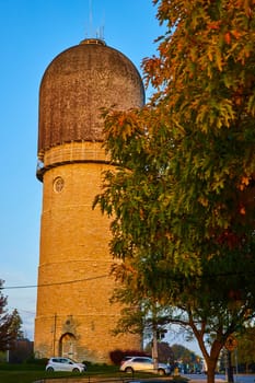 Historic Ypsilanti Water Tower bathed in golden hour light, framed by vibrant autumn leaves, in a charming Michigan town
