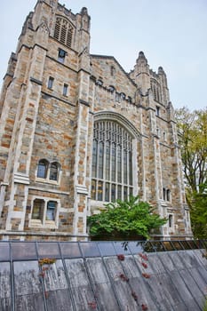 Gothic architecture of the University of Michigan Law Quadrangle, an iconic historical building amidst modern elements in Ann Arbor, under an overcast sky.