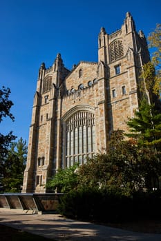 Gothic Revival architecture of University of Michigan's Law Quadrangle under vibrant blue skies, showcasing tradition, history, and academic excellence.