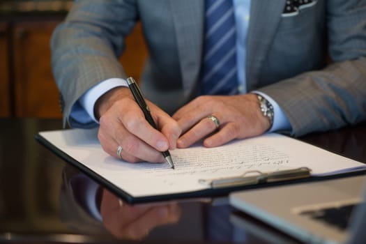 Close up hands of Businessman signing a document on desk, office background, Business concept.