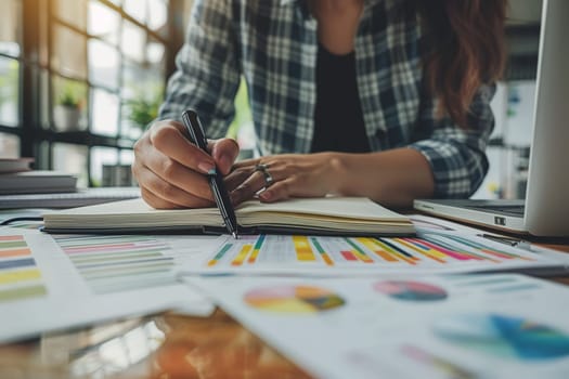 Selective focus on the businesswoman's hand, writing down tasks and note, office background.