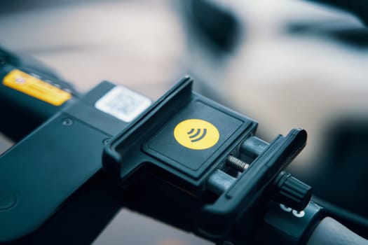A closeup of an electric blue cell phone holder attached to a scooter, serving as a practical motor vehicle accessory and fashionable fashion accessory with a wristwatchlike design
