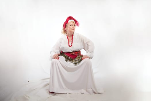 Portrait of cheerful funny adult mature woman solokha. Female model in clothes of national ethnic Slavic style. A stylized Ukrainian, Belarusian or Russian woman poses in a comic photo shoot