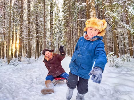 Father and son sledding, having fun, walking in snow nature. Photo shoot in stylized clothes of the USSR. Hat with earflaps. Happy dad, teenager child playing in park, winter forest in holidays