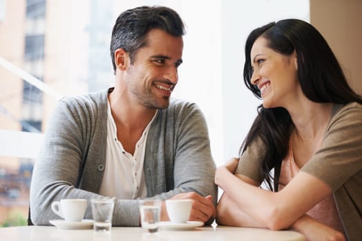 Love, talking and couple with coffee on date for romance or anniversary in cafeteria. Happy, bonding and young man and woman in conversation drinking latte, espresso or cappuccino at restaurant