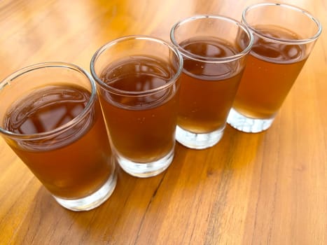 Fresh cold Apple juice in four clear glass with wooden background serves for breakfast