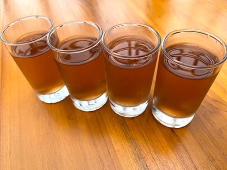 Fresh cold Apple juice in four clear glass with wooden background serves for breakfast