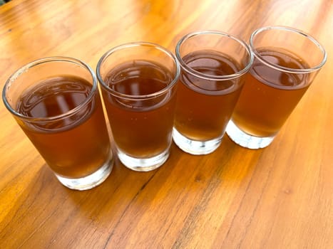 Fresh cold Apple juice in four clear glass with wooden background serves for breakfast