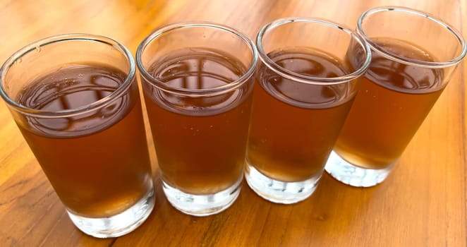 Fresh cold Apple juice in four clear glass with wooden background serves for breakfast