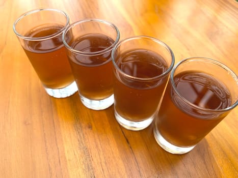Fresh cold Apple juice in four clear glass with wooden background serves for breakfast