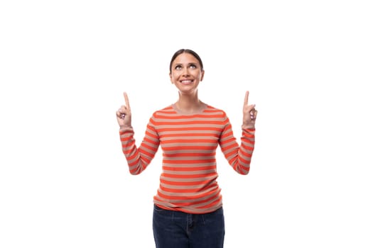 30 year old pretty woman dressed in a casual orange sweater holds her index finger up with surprise.