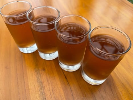 Fresh cold Apple juice in four clear glass with wooden background serves for breakfast