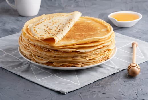 Stack of traditional russian pancakes blini on gray background with copy space. Homemade russian thin pancakes blini. Russian food, russian kitchen.