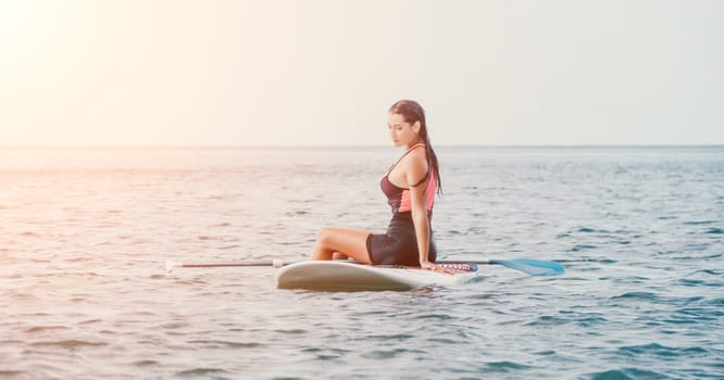 Sea woman sup. Silhouette of happy young woman in pink bikini, surfing on SUP board, confident paddling through water surface. Idyllic sunset. Active lifestyle at sea or river. Slow motion