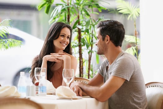 Couple, restaurant and talking on date, love and bonding on valentines day. People, conversation and romance at cafe or smile for anniversary, together and alcohol at bistro on vacation or holiday.