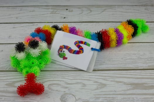 Multi colored snake made of fluffy balls, burdock construction set with hooks for children development, modern toy