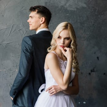 Cute wedding couple in the interior of a classic studio decorated. They kiss and hug each other.