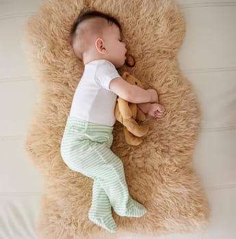 Baby, sleeping and dummy with relax in home for healthy development, growth and tired with top view. Child, rest and pacifier in mouth with nap, dreaming and wellness in nursery of house or apartment.