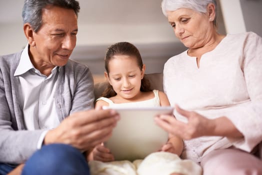 Family, grandparents and girl with tablet for entertainment, social media or research on sofa at home. Grandma, grandpa and child with smile on technology for online search, show or movie at house.