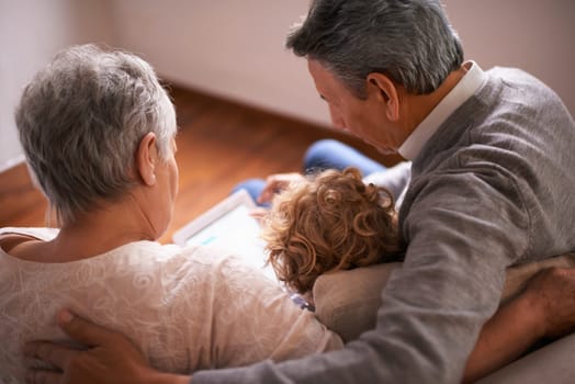 Child, grandparents and tablet on couch for online technology or communication, teaching or connection. Elderly couple, retirement and girl or internet learning in apartment, development or bonding.