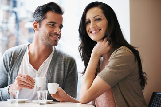 Love, portrait and couple with coffee on date for romance or anniversary in cafeteria. Happy, bonding and young man and woman talking and drinking latte, espresso or cappuccino at restaurant
