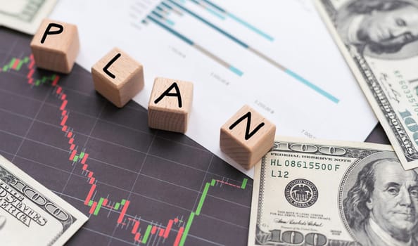 Business concept. On a brown surface are dollars, a calculator and wooden cubes with the inscription - PLAN. High quality photo