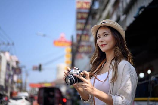 Attractive young female tourist with camera walking on Chinese town street.