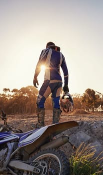 Motorcycle, sports and danger with back view of biker person outdoor, sunlight with uniform for riding on dirt track. Speed, power and risk with motorbike, transportation and adventure for adrenaline.
