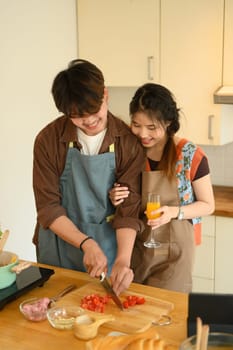 Shot of happy young couple wearing aprons making delicious bolognese sauce for dinner in kitchen.