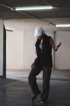 Portrait of talented woman performing various freestyle dance in parking garage.